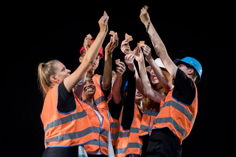 group of students wearing orange high vis jackets with their hands in the air