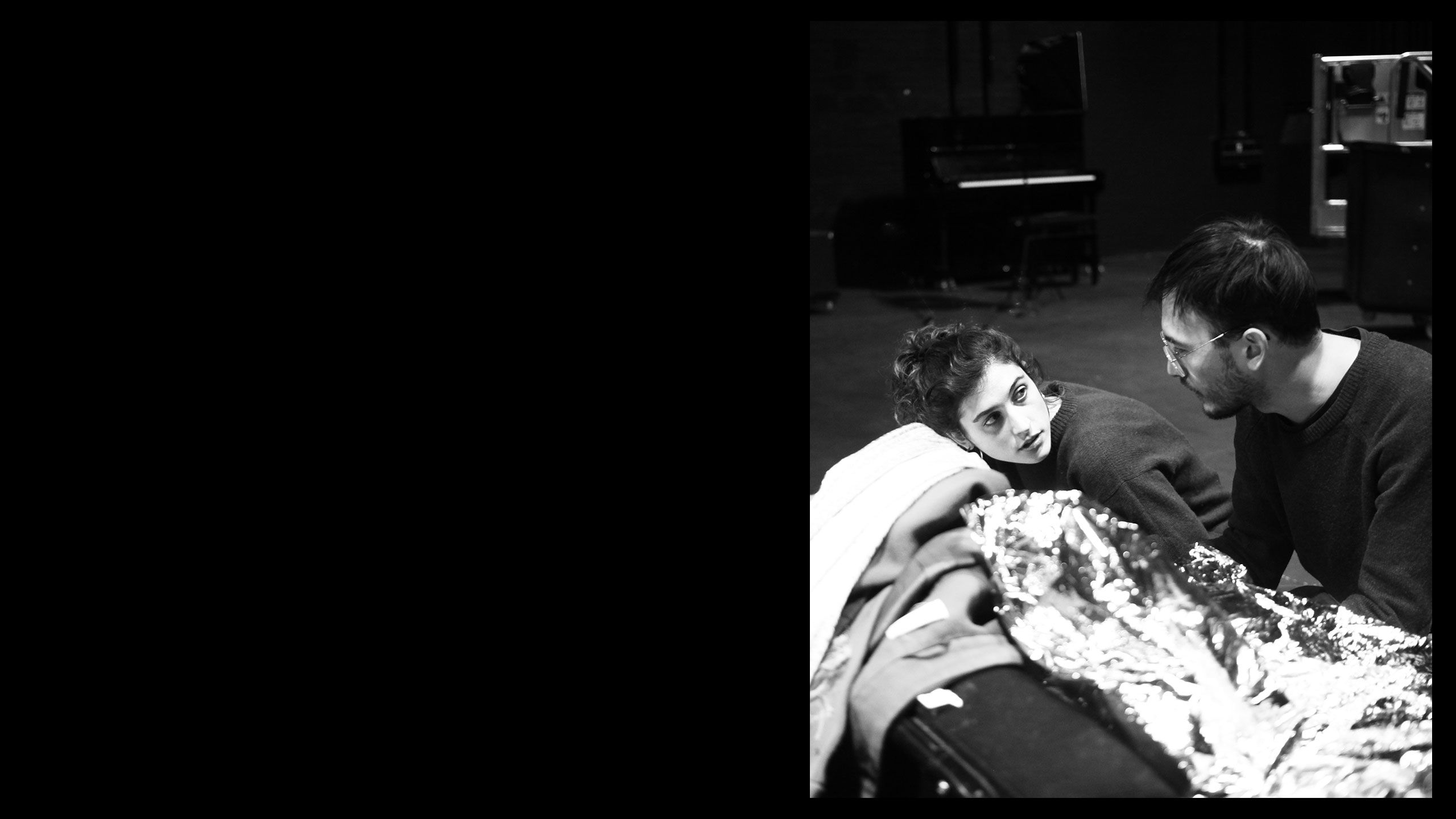 black and white photo of two people on the floor holding on to a thermal blanket