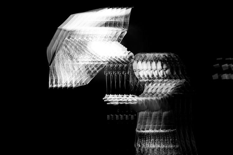 black and white glitch version of girl holding a lamp in the dark