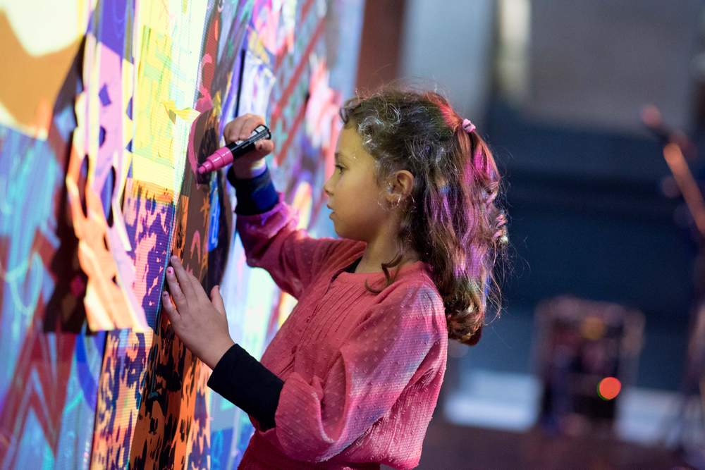 A young visitor makes her mark on Antonio Roberts glitch-art wall © Camilla Greenwell